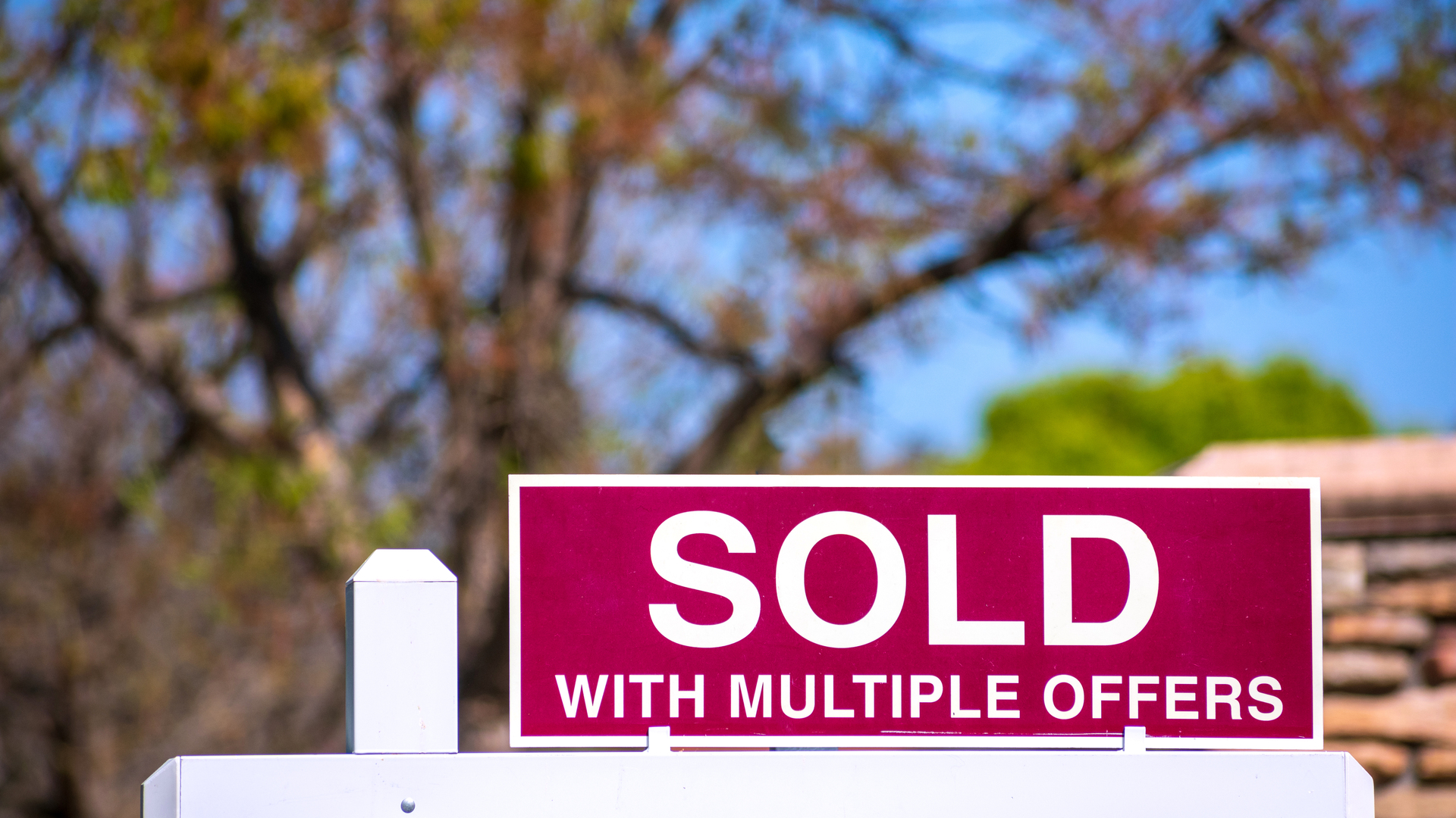 SOLD With Multiple Offers real estate sign near purchased house.