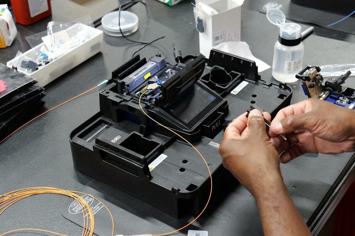 BICSI technician performing precision fiber optic splicing and cable termination on site