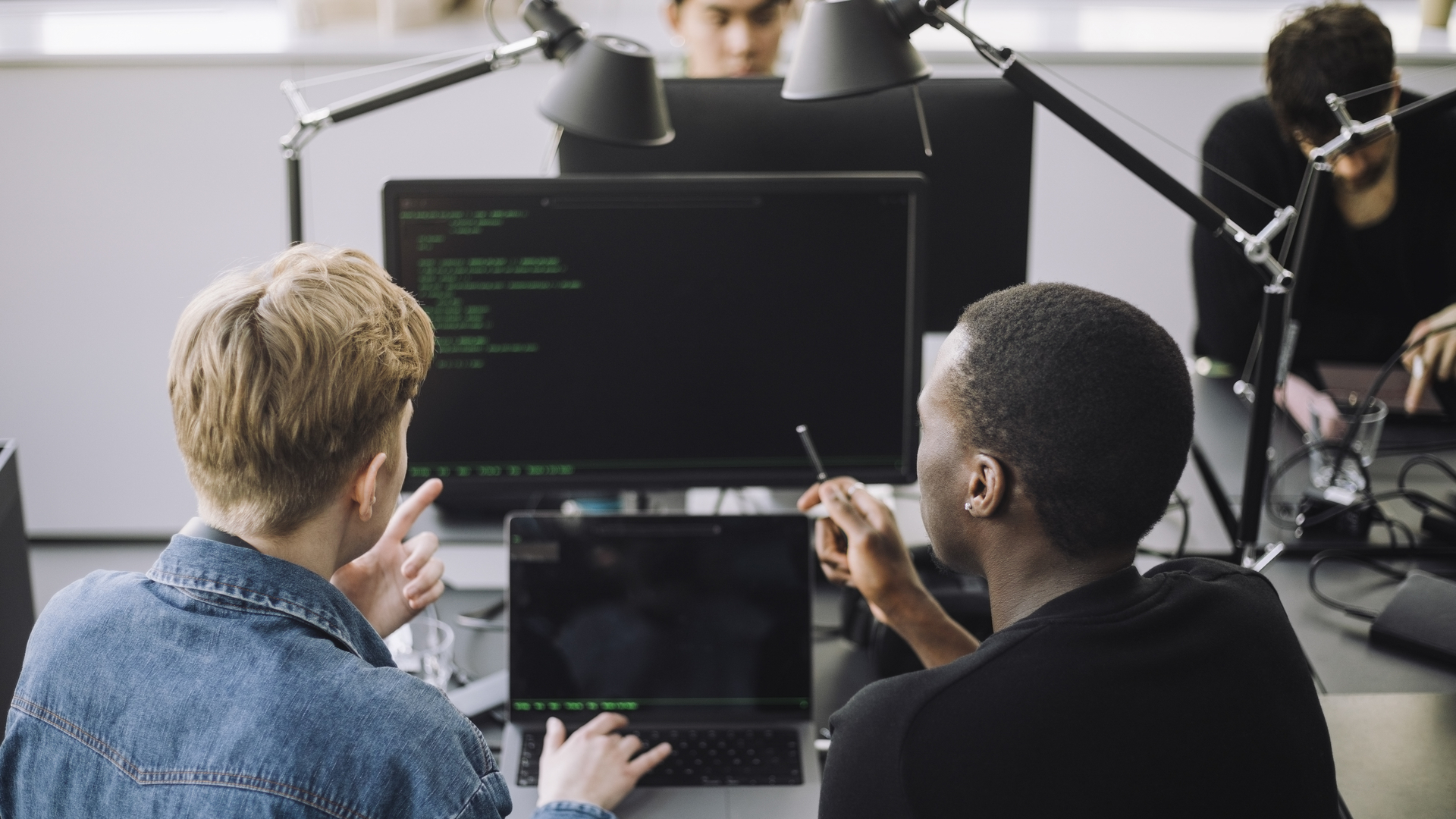 Male computer programmers discussing over codes at desk in office