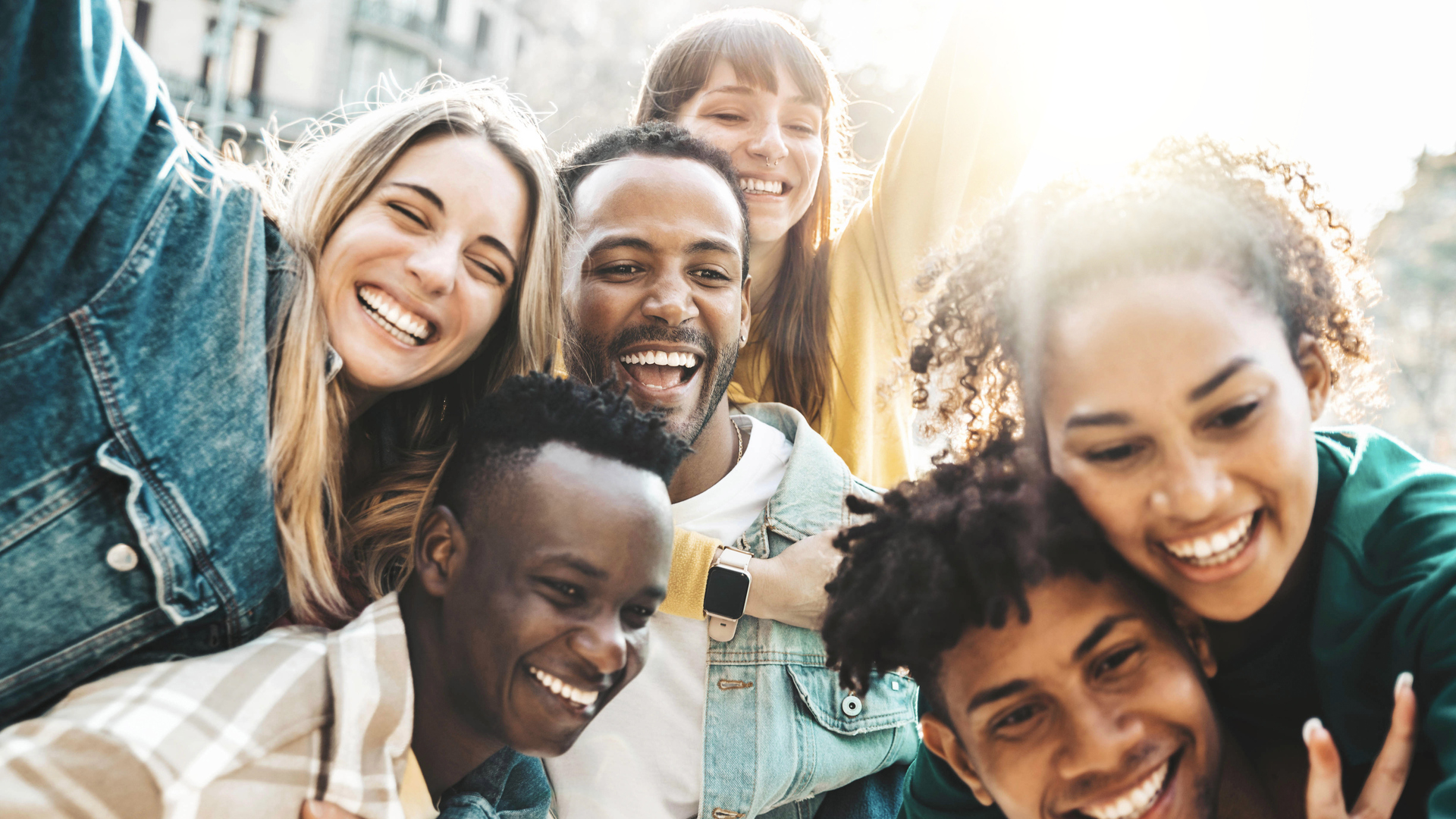 Happy multiracial friends having fun hanging out on city street - Group of young people laughing out loud together outside - Friendship concept with guys and girls enjoying weekend