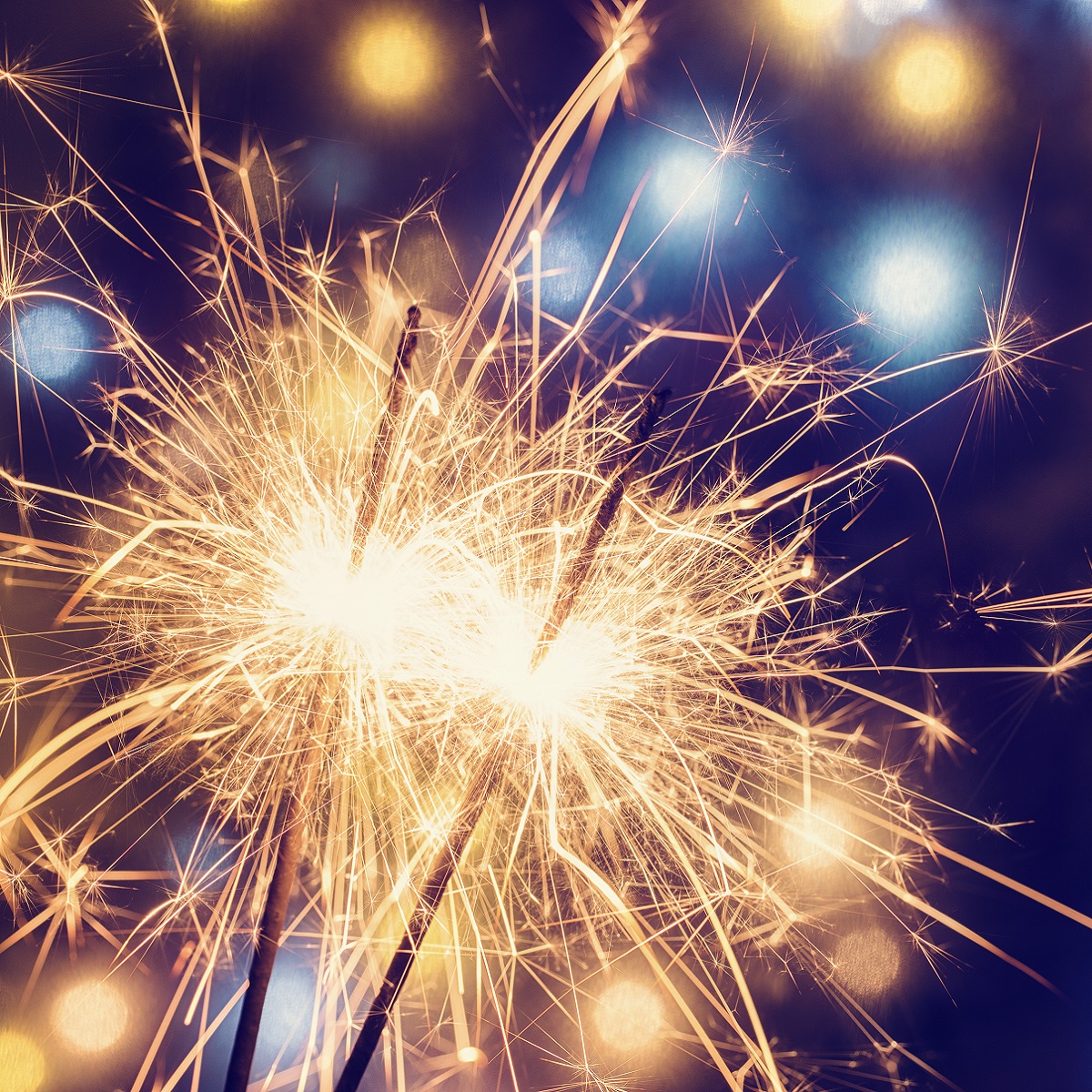 Two sparklers emit bright, celebratory sparks