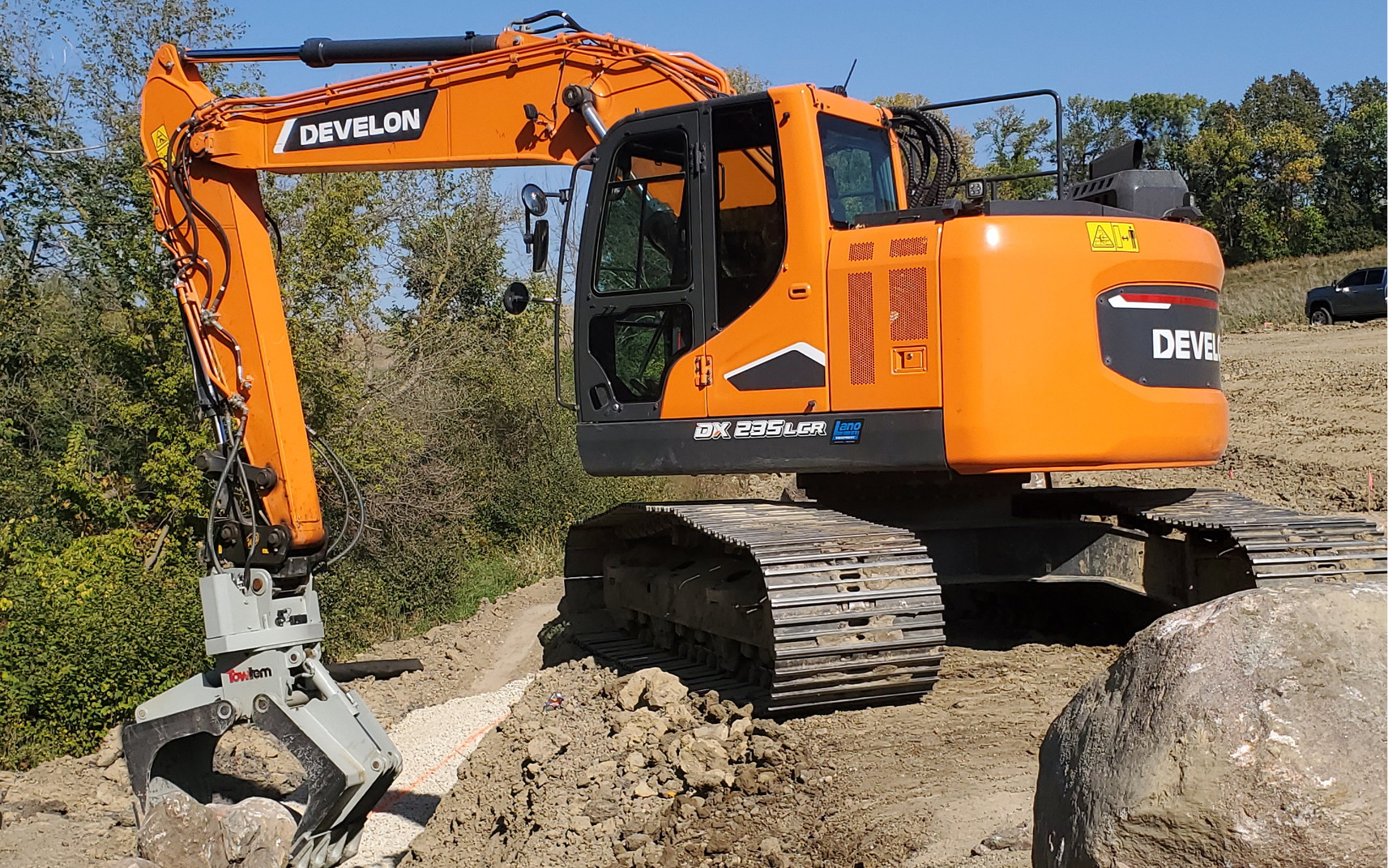 A DEVELON DX235LCR-7 crawler excavator picking up rocks. 