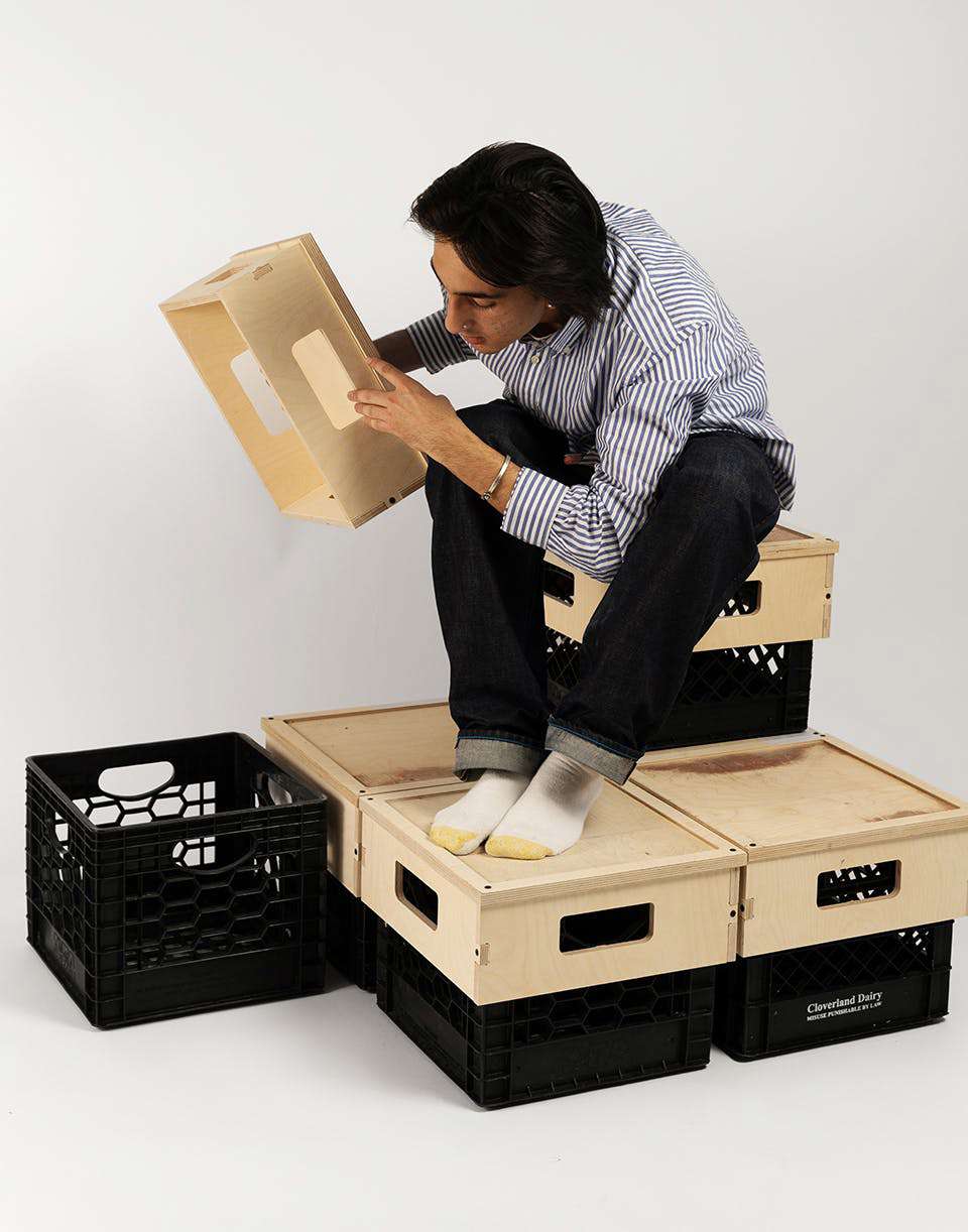 Photograph of Acuña arranging and working with empty milk crates and wooden blocks.