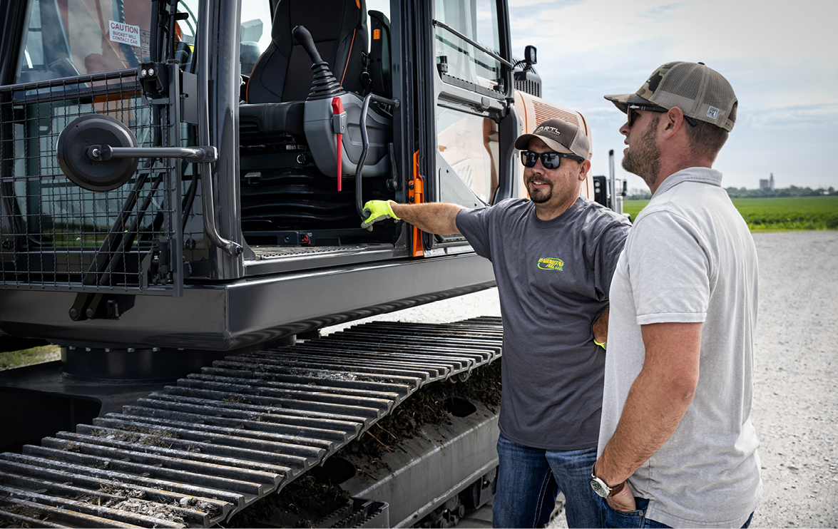 A sales specialist answers a customer’s questions about a DEVELON excavator.