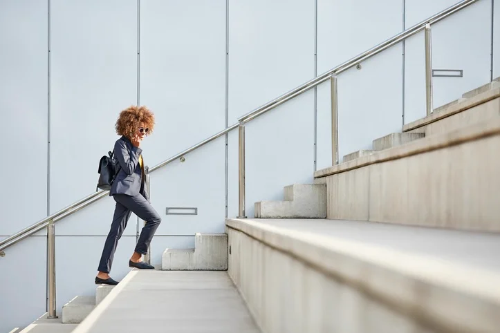 Services leader walks up a large outdoor staircase to her office