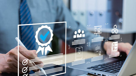 Professional using a stylus and laptop with digital quality assurance certificate overlays