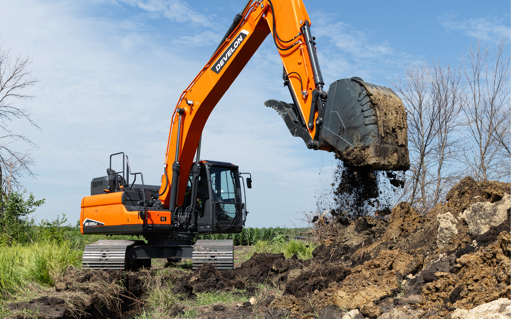 On a construction job site, a crawler excavator operator empties dirt from the bucket.