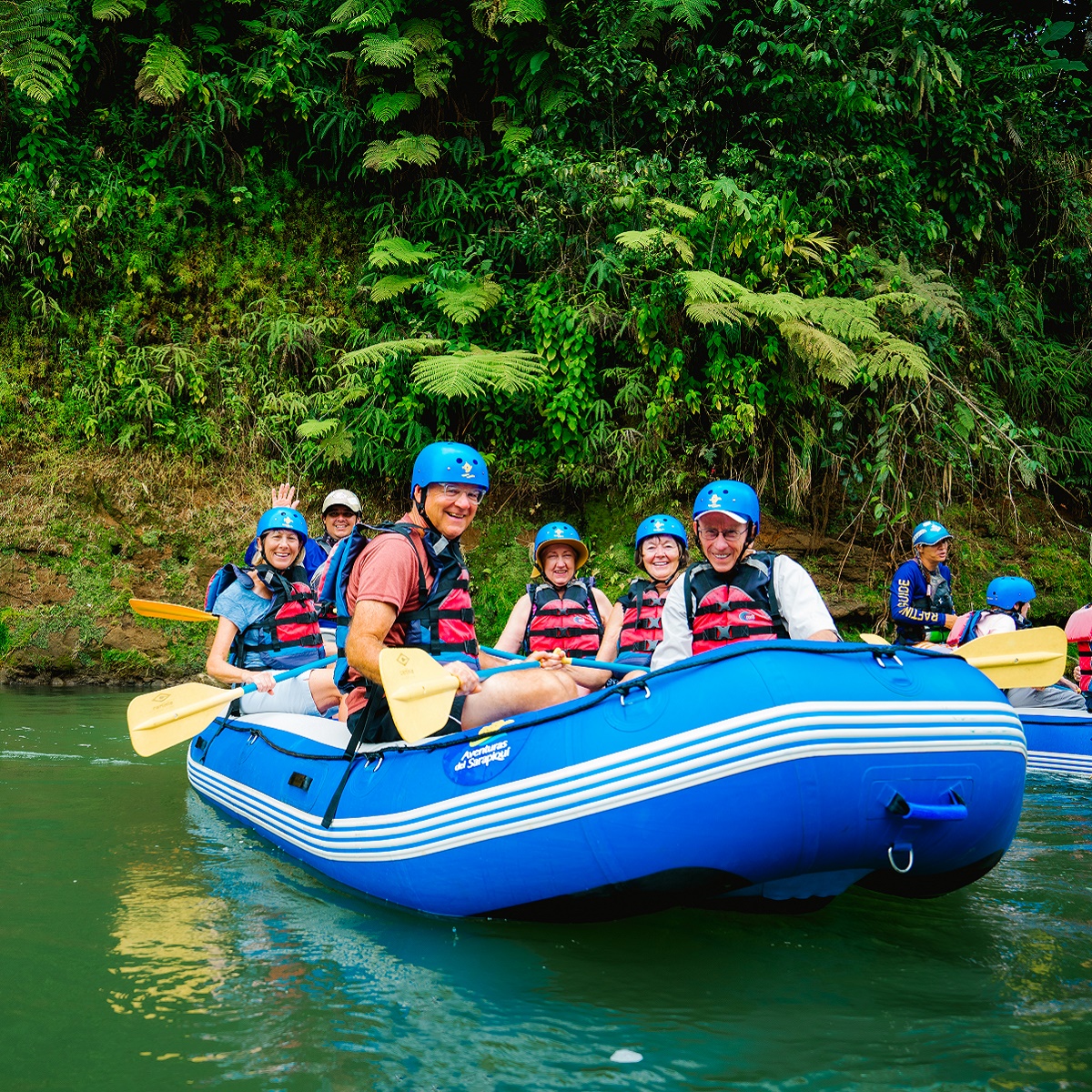 A group smiles from a blue raft in the middle of a river in Costa Rica