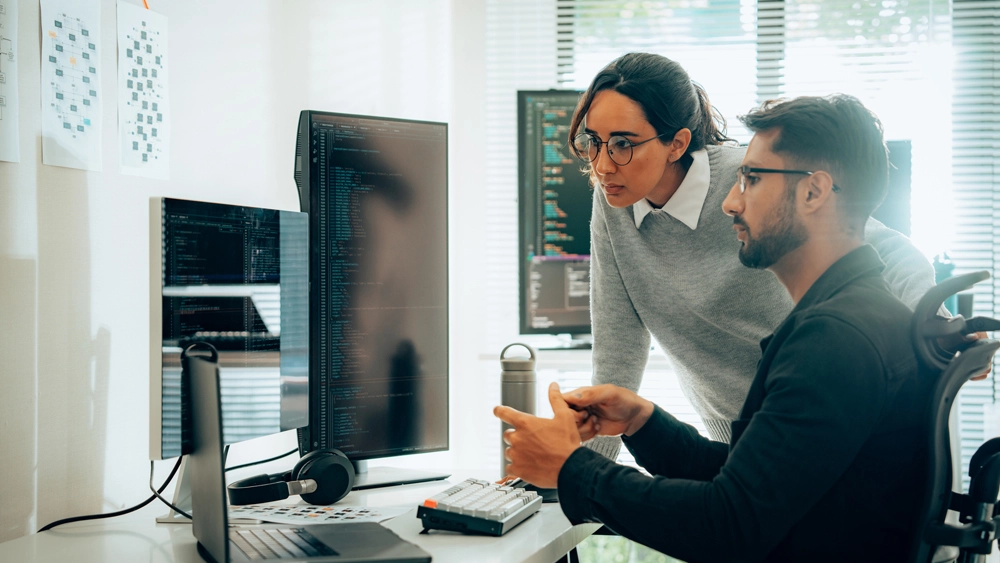 Stock image of two office workers looking at desktop
