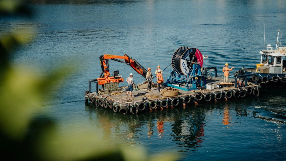 Photo of Vocus Networks workers - on the water. There's a Vocus logo visible on the fibre cable