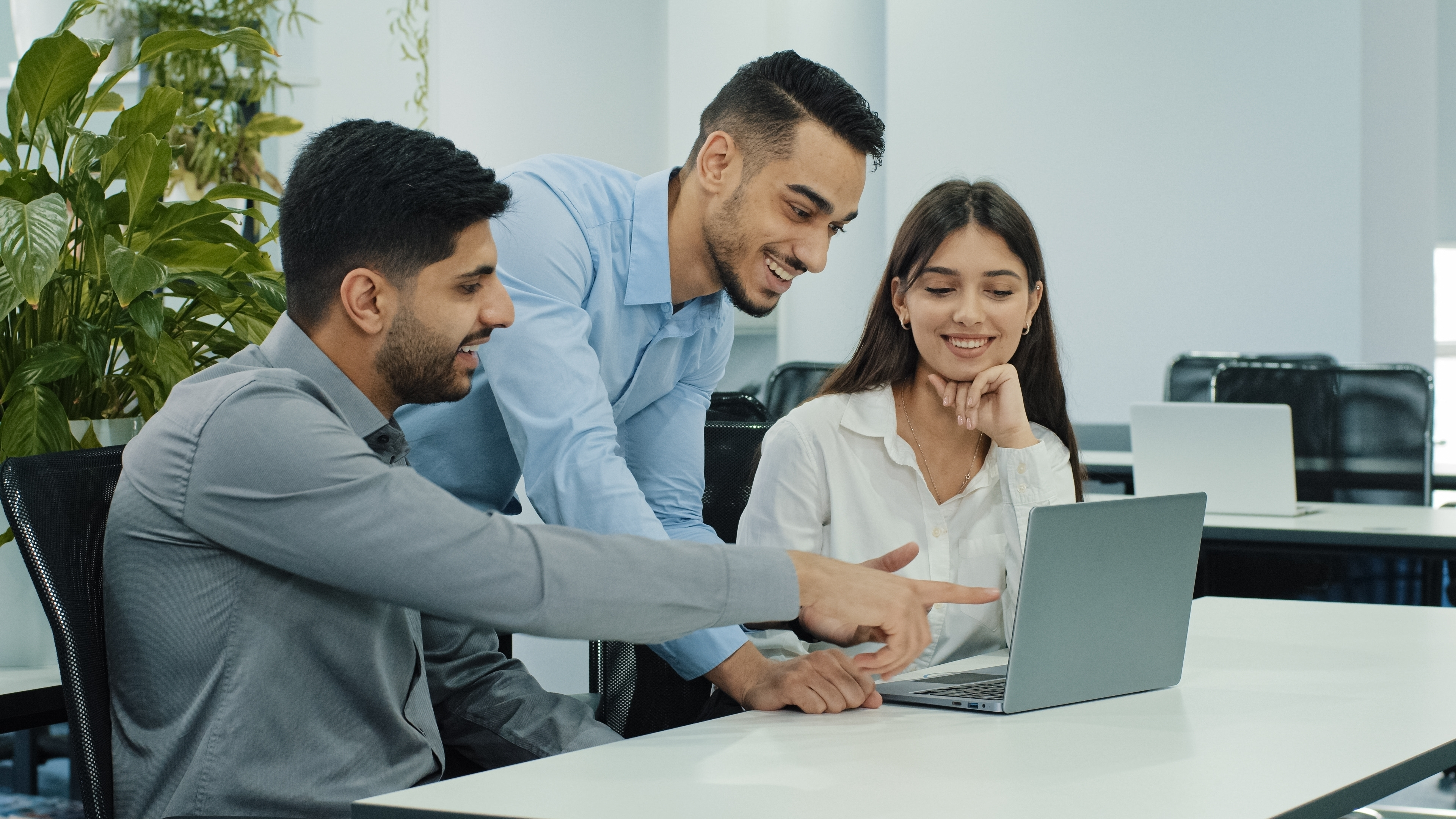 This is a stock photo image of three team members in an office working at a computer