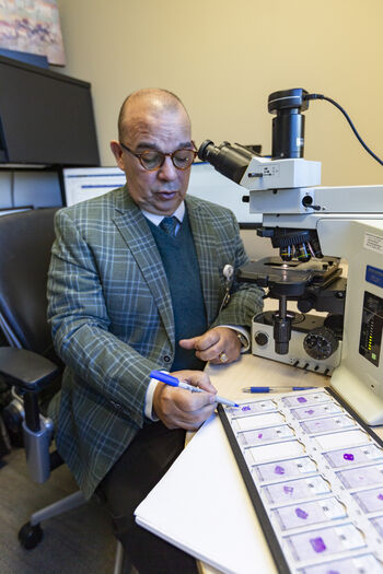 Pathologist Alex Lopez, MD, reviews slides with donated tissue samples and marks areas to be saved for research. 