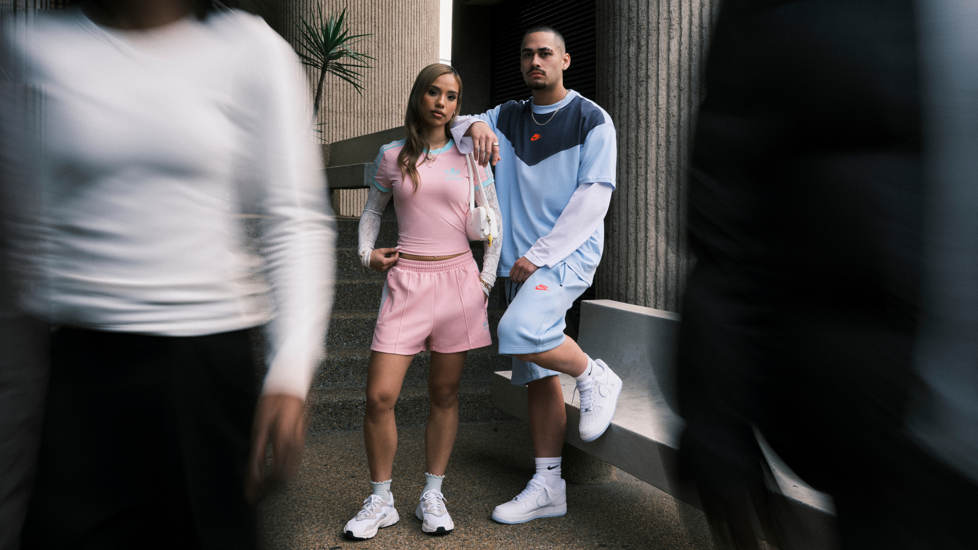 Woman wearing pink Adidas set with blue stripes. Man wearing blue Nike set
