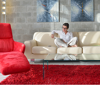 Ženska sedi na kavču v moderno urejenem in pospravljenem domu in bere revijo