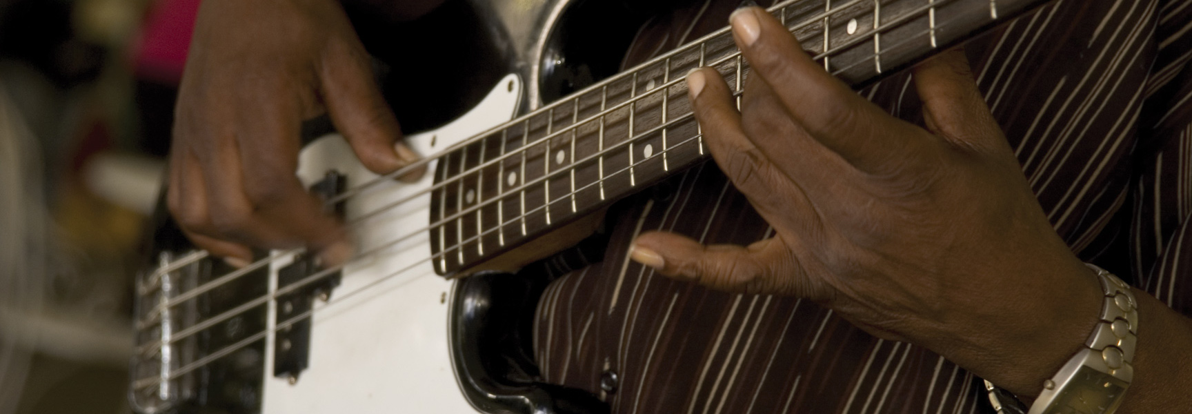 Close-up of a musician's hands playing the bass guitar at the French Quarter Music Festival in New Orleans.