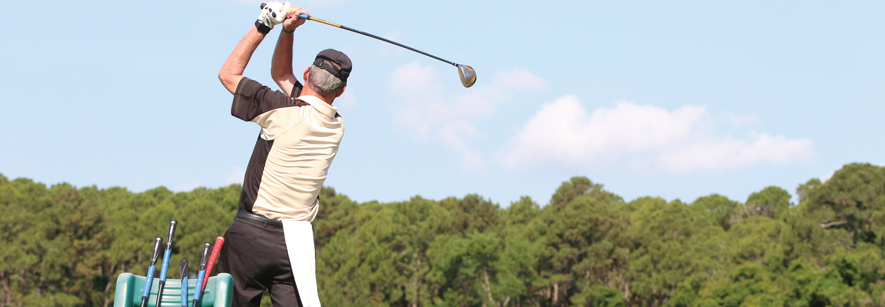 A golfer at the top of his backswing on a beautiful, sunny golf course in Georgia.