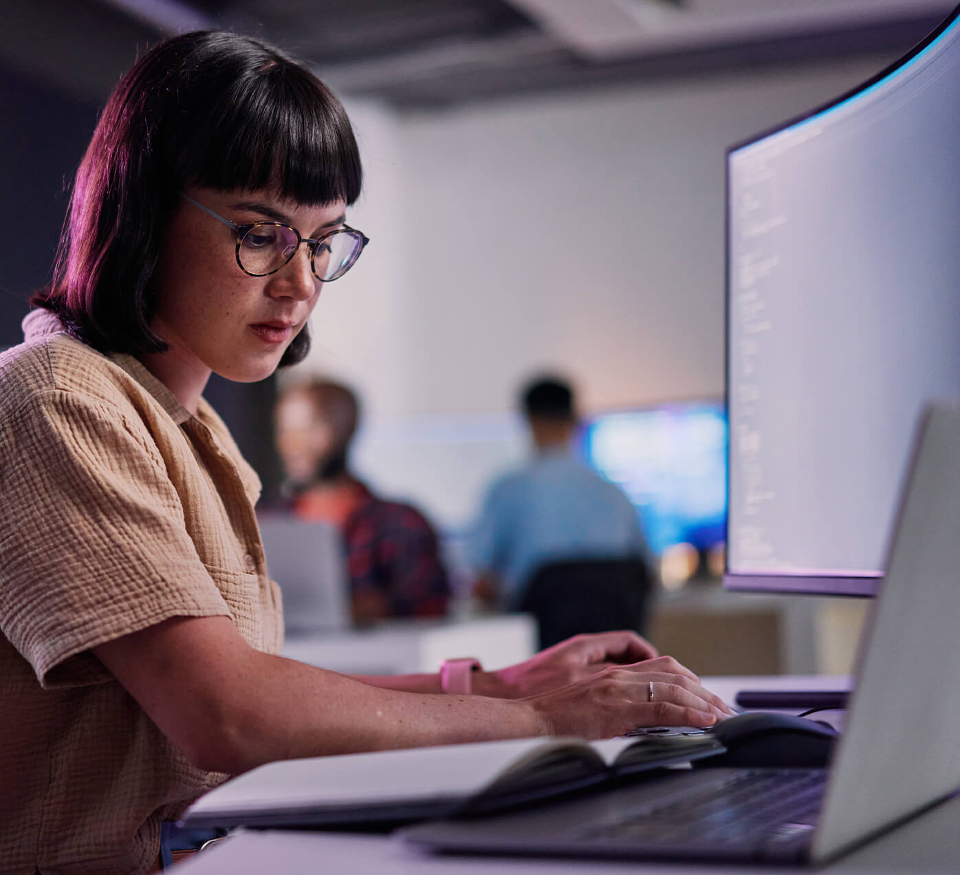 Woman sitting at a desk typing on a laptop computer.