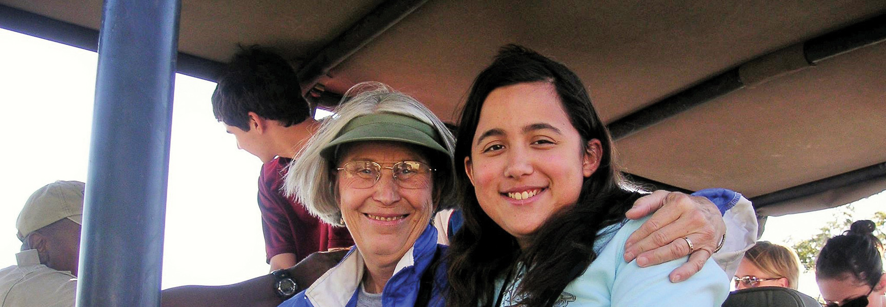 A grandmother and her grandchild smile for the camera while on a safari vehicle in South Africa, Zambia, or Botswana.