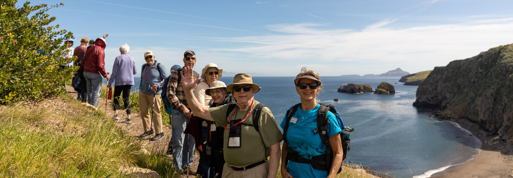 A group of hikers stands on a ridge overlooking the coastline and beach at Santa Cruz Island in California's Channel Islands National Park.