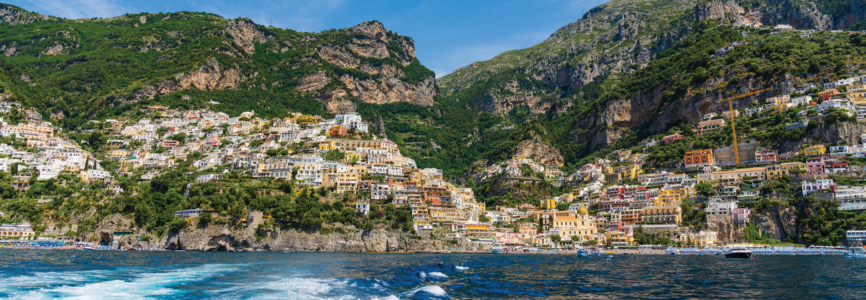 A view from the water of the colorful, vibrant buildings built into the cliffs of the Amalfi Coast in Italy.