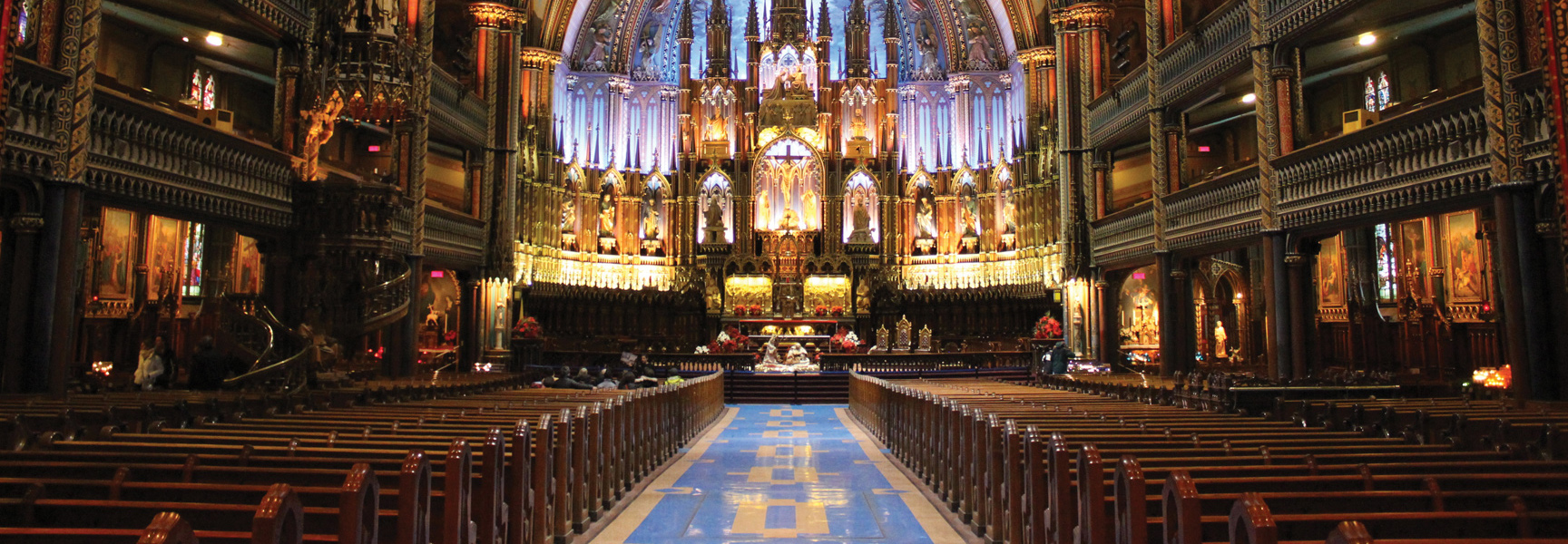The view down the main aisle towards the ornate, illuminated altar of the Notre-Dame Basilica in Montréal, Québec.