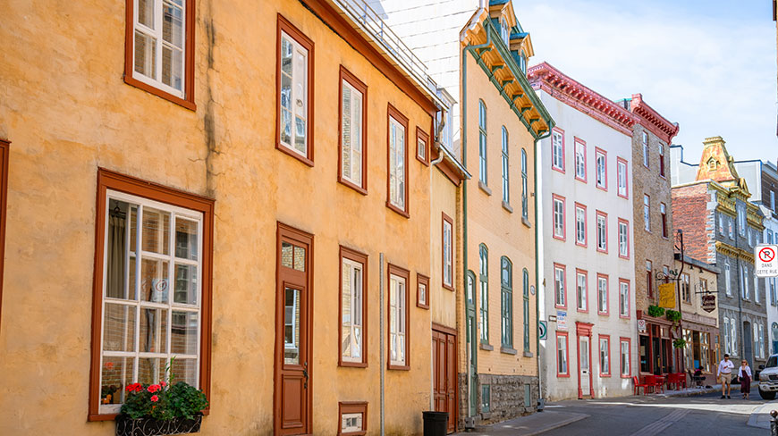 Colorful historic buildings line a narrow street in the Old City of Québec during a walking tour.