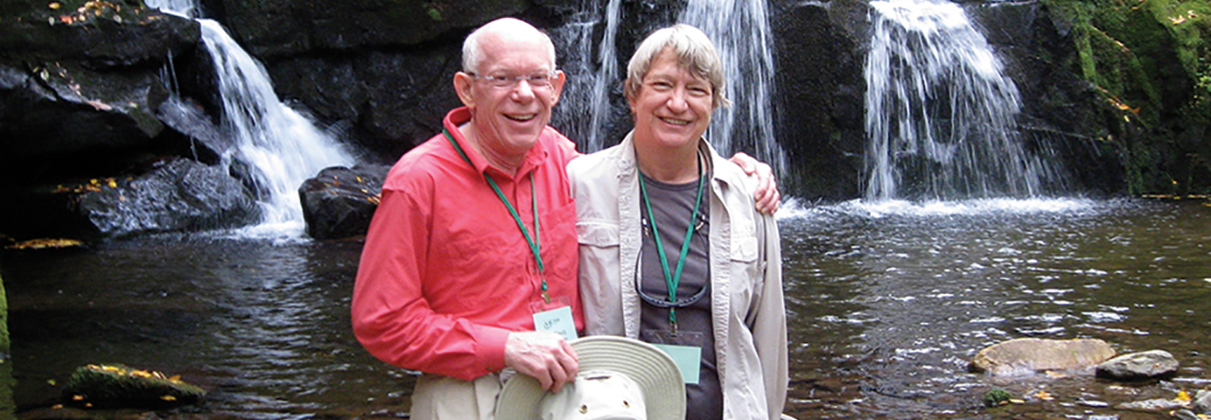 An older couple smiles for a photo in front of a waterfall in Tennessee.