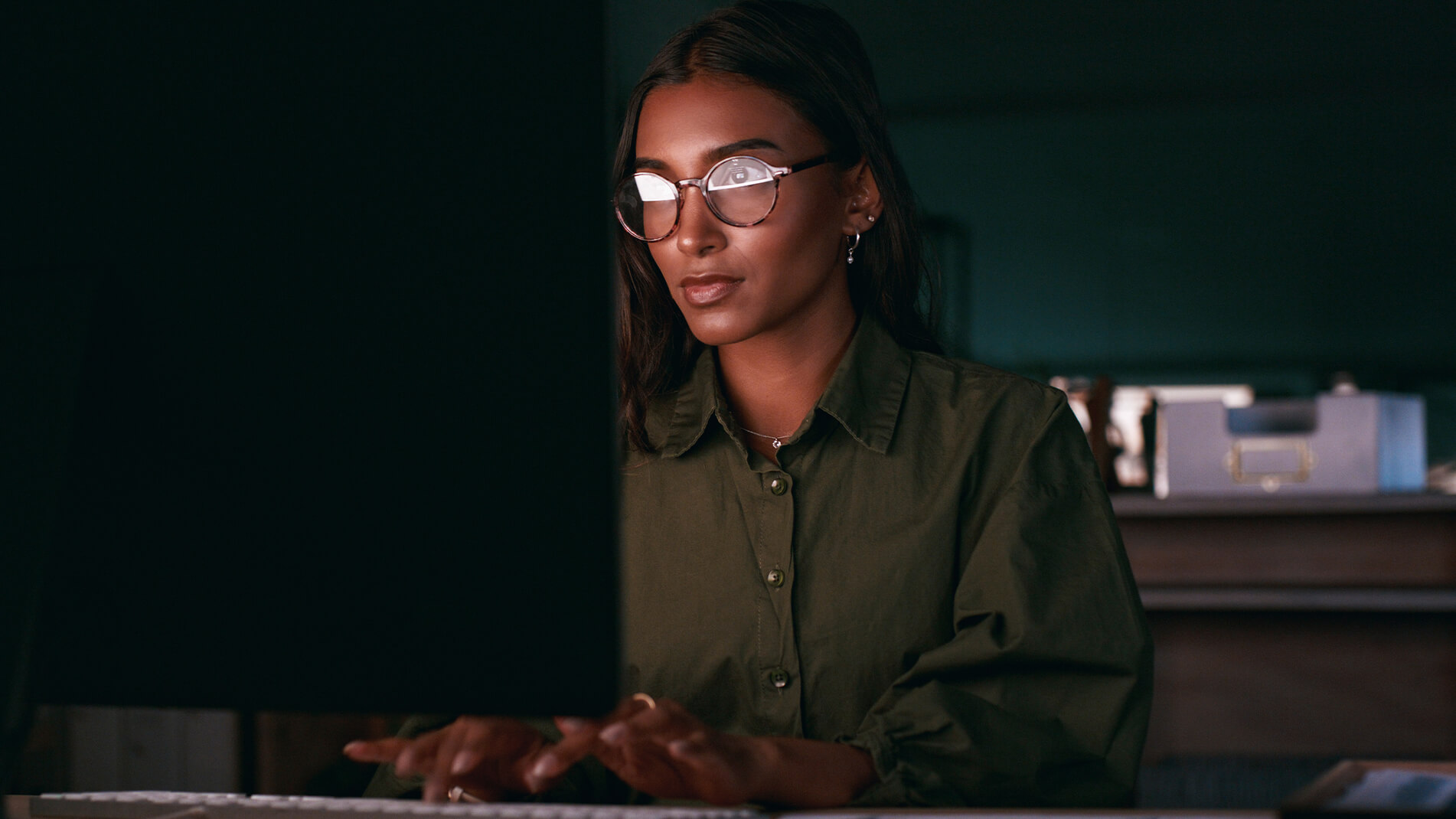 Image of person wearing glasses typing on keyboard.