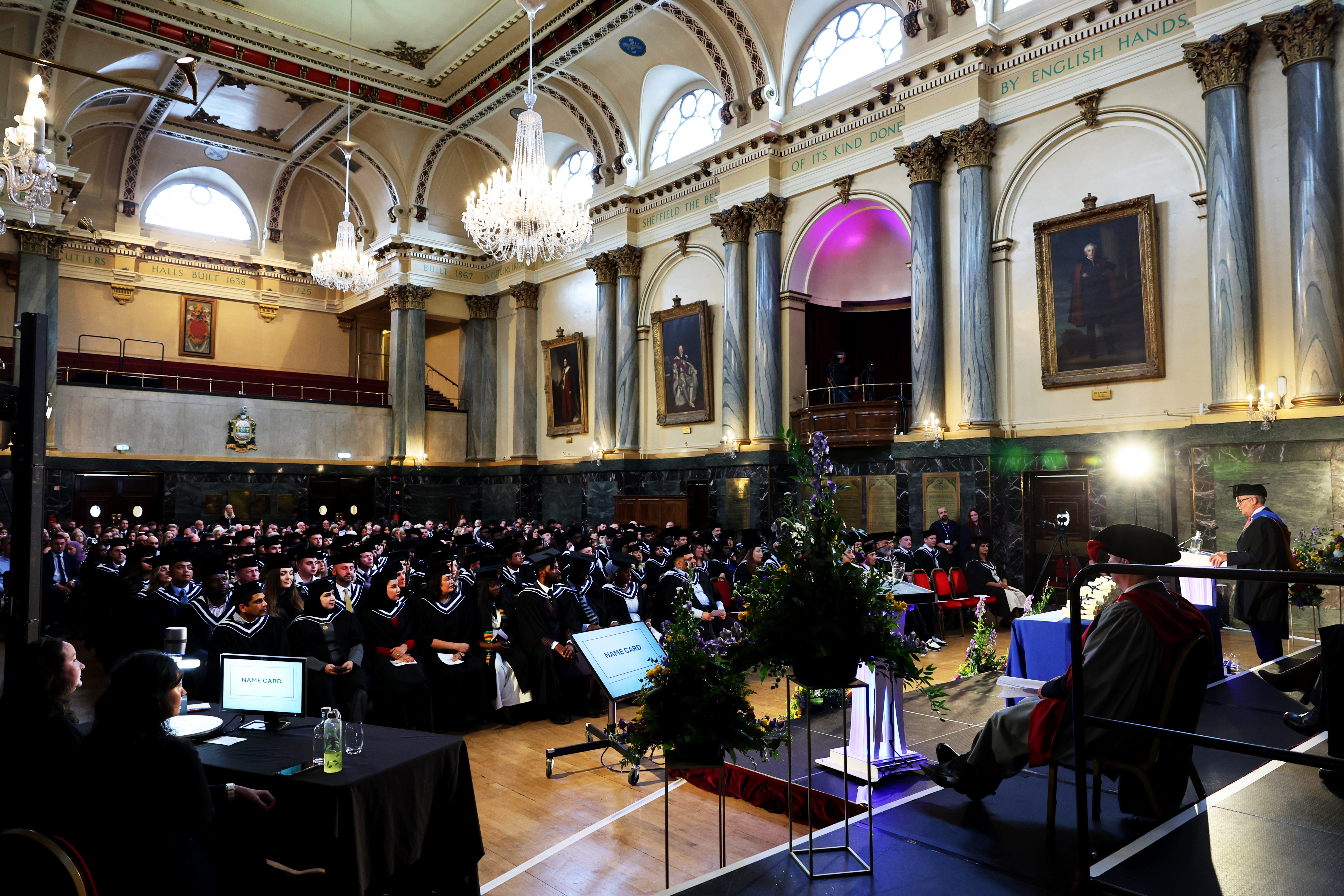 Wide-angle view from the stage looking out at rows of seated graduates in caps and gowns during a ceremony.