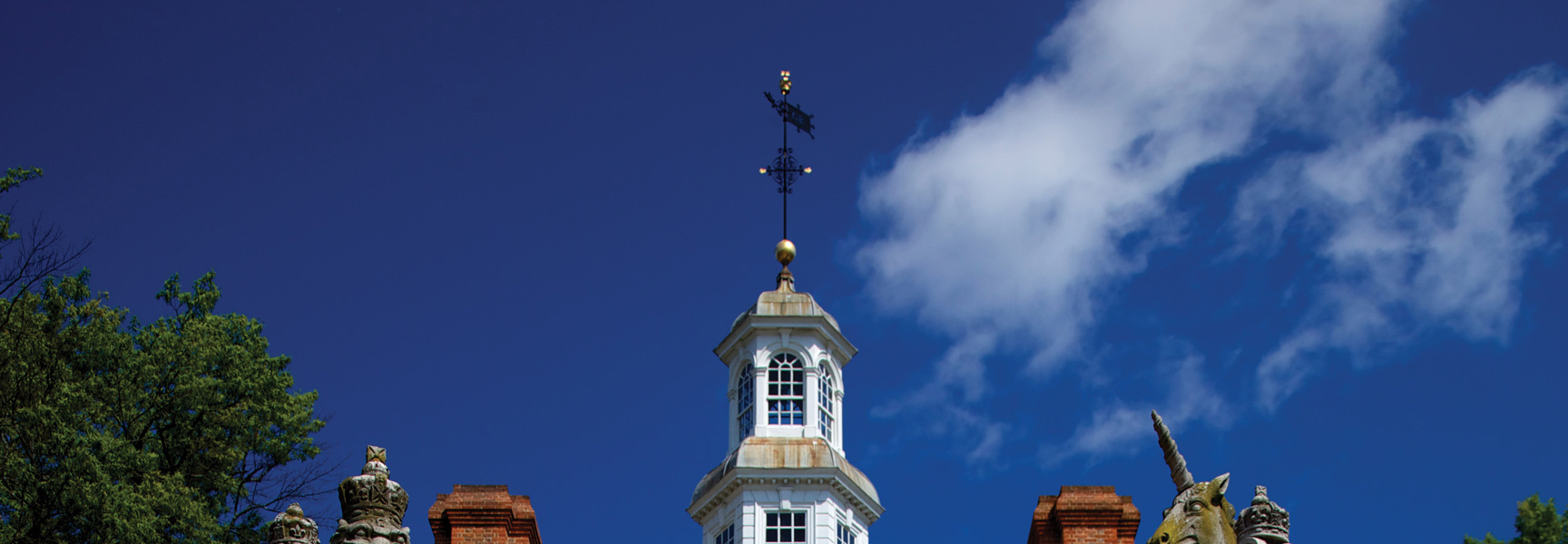 A white colonial-style cupola with a weathervane against a bright blue sky in Virginia.