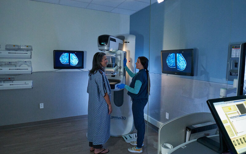 An oncological-trained technologist is explaining mammograms to a woman.