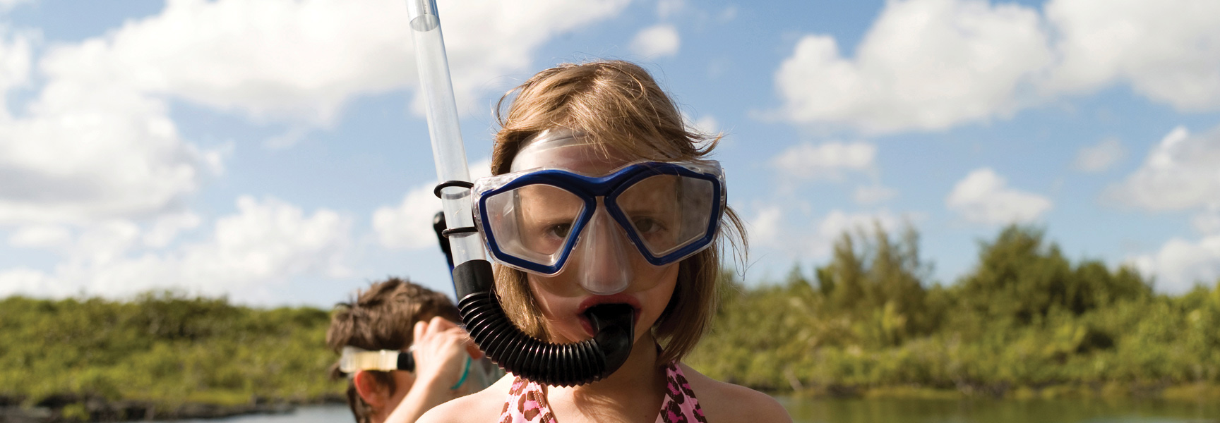 A young grandchild in a blue snorkel mask gets ready for a snorkeling adventure with family in Key Largo, Florida.