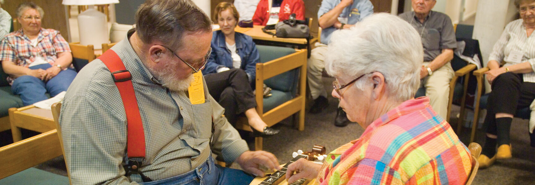 A man and woman play a double-necked mountain dulcimer together during a music workshop in the Great Smokies of Tennessee.