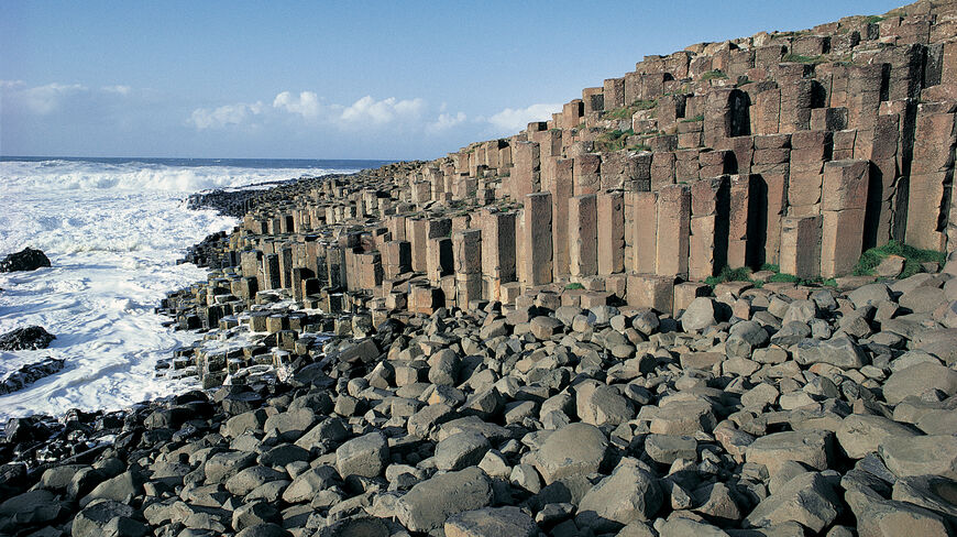 The interlocking basalt columns of Giant's Causeway on the coast of Northern Ireland meet the crashing waves of the sea.