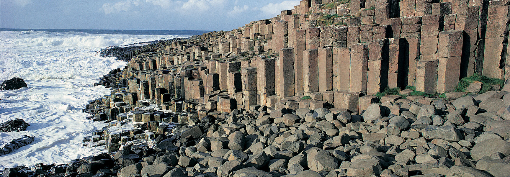 The interlocking basalt columns of Giant's Causeway on the coast of Northern Ireland meet the crashing waves of the sea.