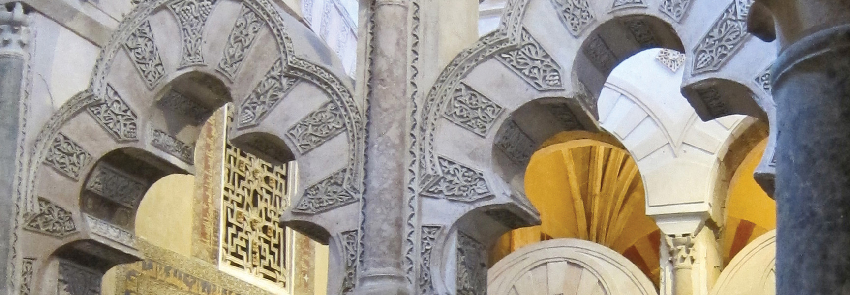 Intricate Moorish arches with detailed stone carvings create a stunning architectural display inside a historic building in Spain.