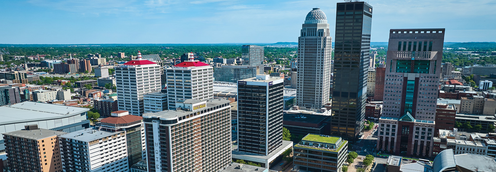 An aerial view of the downtown Louisville, Kentucky cityscape on a bright, sunny day.