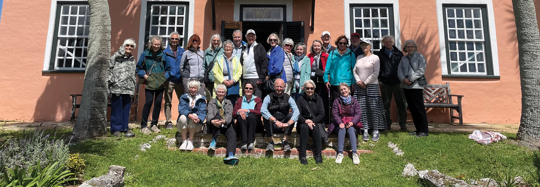 A group of travelers poses for a photo on the steps of a historic building in Bermuda.