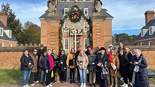 A group of travelers poses for a photo in front of the Governor's Palace in Virginia, which is decorated for Christmas.