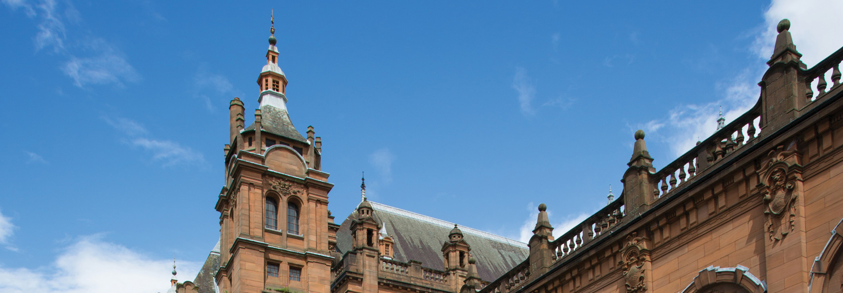 The rooftop of a grand, historic building in Scotland under a clear blue sky.