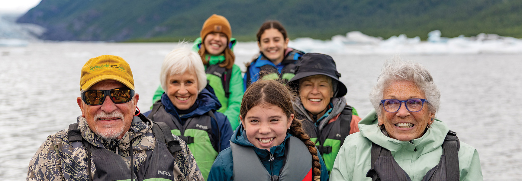 Grandparents and grandchildren smile while on a boat tour exploring glaciers in Alaska.