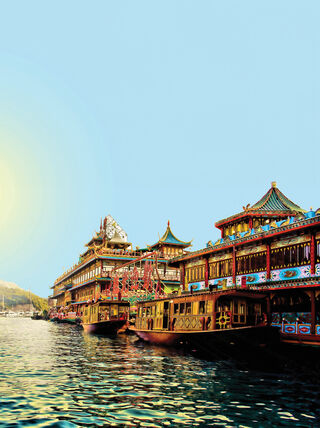Ornate, multi-story traditional Chinese floating structures docked on calm water under a bright sun during a World Academy global learning journey.