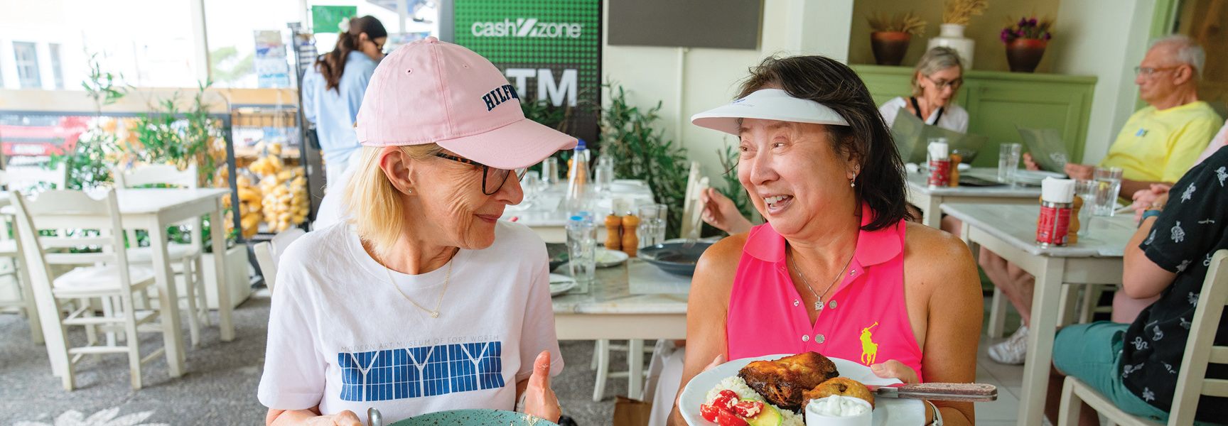Two women enjoy a meal and conversation at an outdoor cafe in Turkey or Greece.
