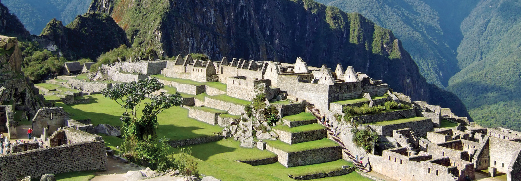 The ancient stone city of Machu Picchu sits on green terraces carved into the steep mountains of Peru.