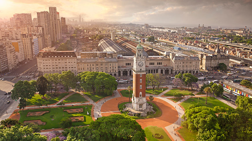 An aerial view of the Torre Monumental clock tower and surrounding Plaza San Martín in Buenos Aires, Argentina at sunset.