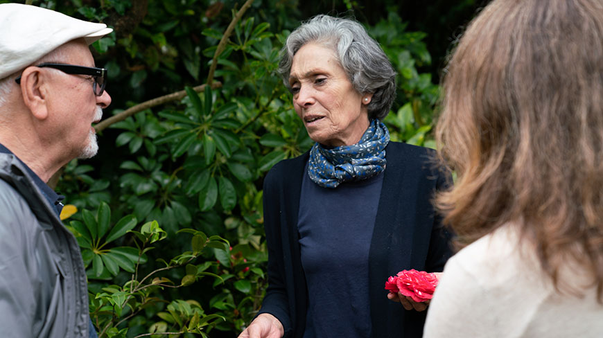 A group leader speaks with two participants during a program in a lush garden in Costa Rica.