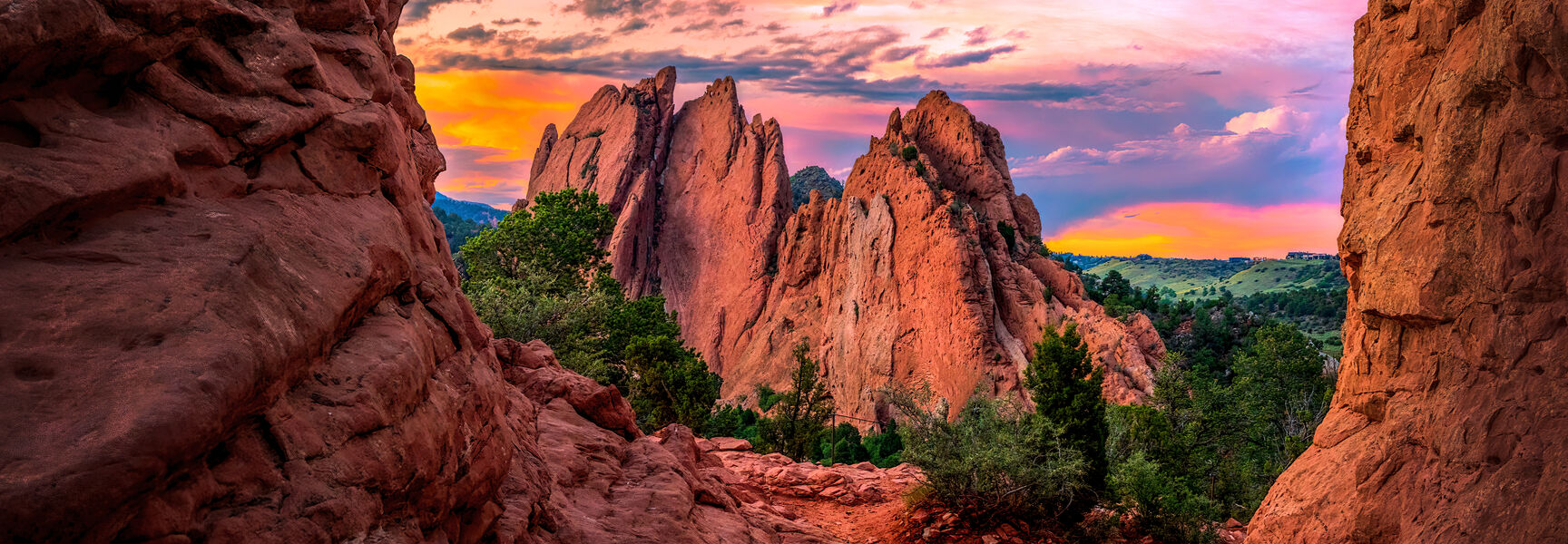 Vibrant pink and orange sunset sky over the towering red rock formations of Garden of the Gods in Colorado Springs, Colorado.