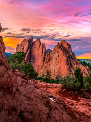 Vibrant pink and orange sunset sky over the towering red rock formations of Garden of the Gods in Colorado Springs, Colorado.