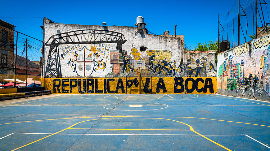 A blue outdoor sports court in the La Boca neighborhood of Buenos Aires featuring a mural with the text Republica de la Boca.