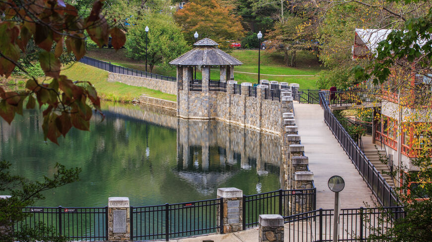 A stone walkway and gazebo overlook Lake Susan at the Montreat Conference Center in North Carolina, surrounded by lush trees.